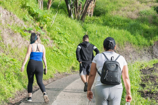 Latina-Familienmutter mit ihren zwei Kindern, die einen Morgenspaziergang auf einem ökologischen Pfad machen