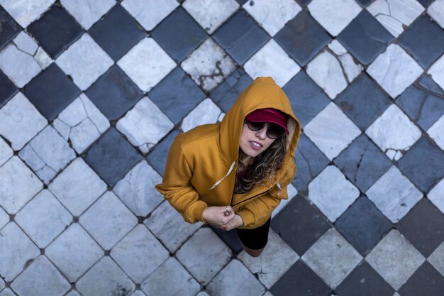 Latina-Frau mit lockerem Haar, Kapuzenkapuze, Sonnenbrille, Zenithal View, Dreieck, Hintergrund bnw