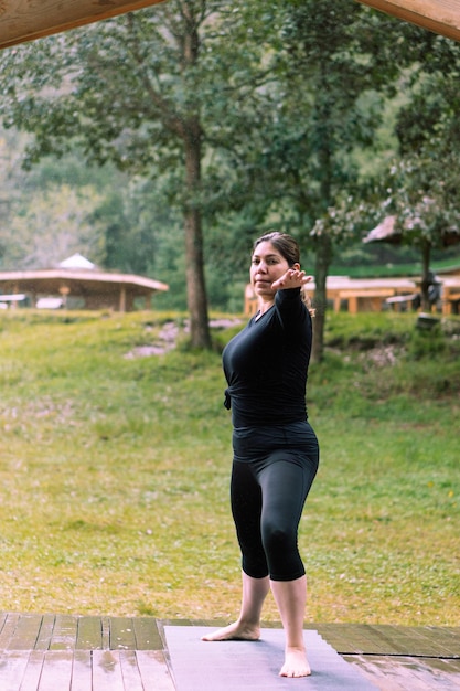 Latina-Frau praktiziert Yoga und Dehnübungen in einem Park.