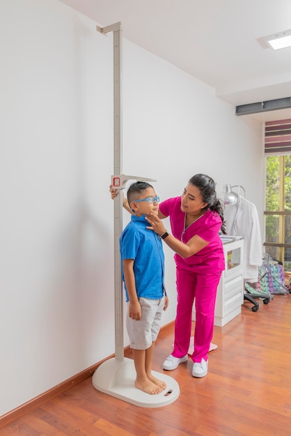 Latina-Kinderärztin misst ein Kind mit einem Wandlineal in ihrem Büro