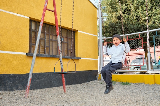 Foto latino-kind spielt auf der schaukel in einem park im freien in la paz, bolivien