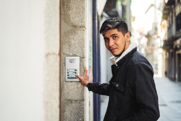 Latino-Mann klingelt an einer Gebäudetür