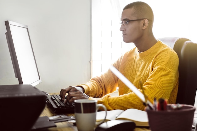 Foto latinoamericano escribiendo o trabajando en su computadora de escritorio concepto de trabajo remoto