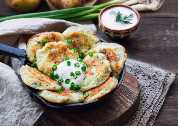 Latkes de panquecas de batata frita caseira fresca em frigideira de ferro em madeira rústica. comida judaica tradicional para a celebração de hannukah.