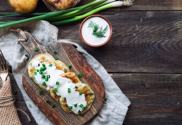 Latkes de panquecas de batata fritas caseiras frescas na tábua de madeira rústica. Comida judaica tradicional para a celebração de Hannukah. Vista do topo.