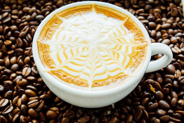 Latte art, Close-up de uma linda xícara de café quente no fundo do feijão de café