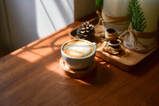 Latte art coffee en mesa de madera luz del sol en la ventana