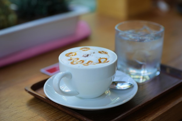 Latte art em xícara de café cappuccino na mesa de café Closeup de desenho de flor de roseta em espuma