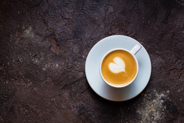 Latte art heart en taza de capuchino. Vista superior sobre fondo de hormigón marrón