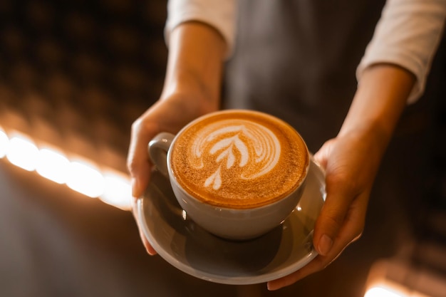 Latte art na mão do barista pronto para beber na cafeteria moderna