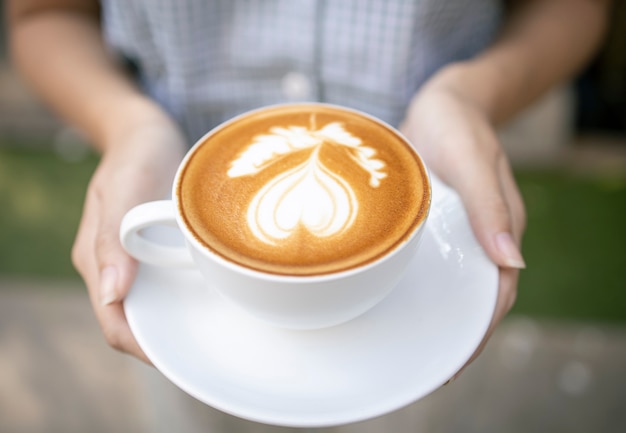 Latte art en una taza de café con leche sobre una mesa de madera