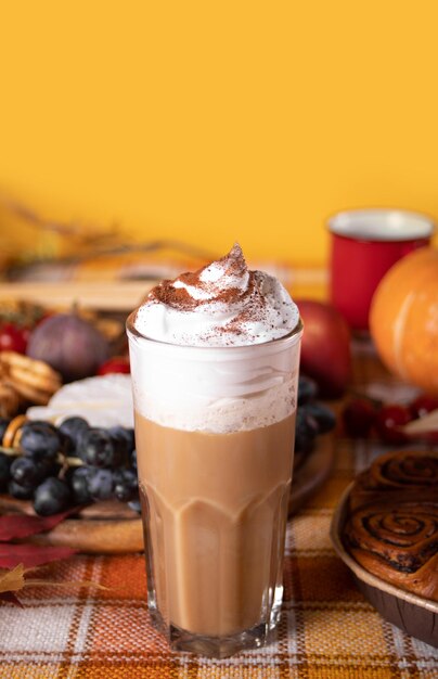 Foto latte batido con especias de calabaza en vasos bebida caliente de otoño cerca de deliciosos pasteles y aperitivos, frutas y queso