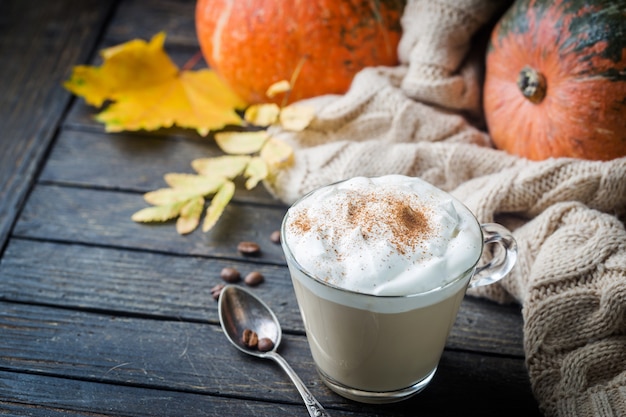 Latte de calabaza con crema batida y especias con calabazas y suéter acogedor