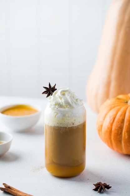 Latte de calabaza con crema batida en un vaso en el fondo de calabazas