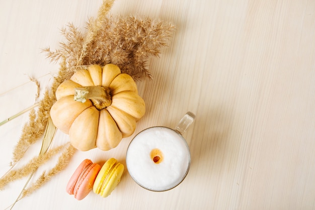 Latte de calabaza y especias. Taza de Latte con calabaza, macarrones y decoración otoñal. Bebida de café tradicional de otoño con galletas.