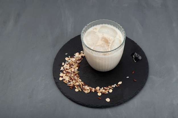 Latte coreano Misugaru con cubitos de hielo en placa negra sobre fondo gris