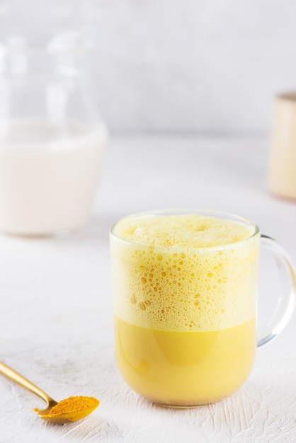 Latte de cúrcuma batido con leche de almendras, jengibre, cúrcuma y canela en una taza sin azúcar ni lactosa