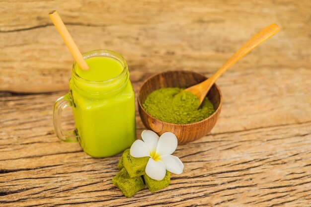 Latte de chá verde com gelo em pó matcha de pote de pedreiro e doces feitos de matcha em fundo de madeira