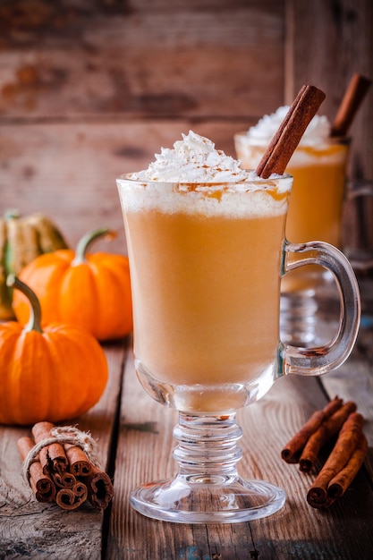 Latte de especiarias de abóbora com chantilly na mesa de madeira