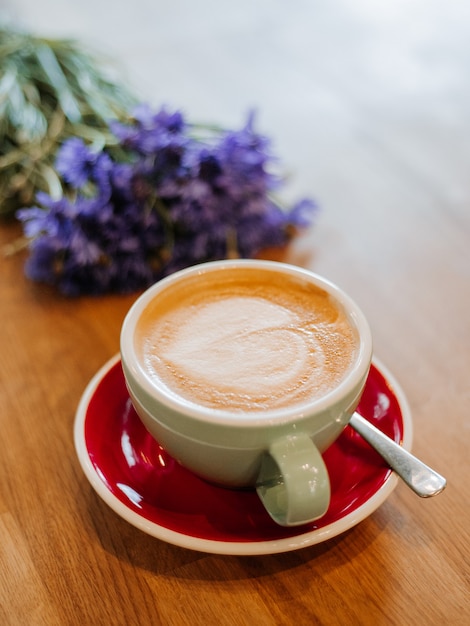 Latte en escritorio de madera con flor aciano en efecto de filtro de película retro