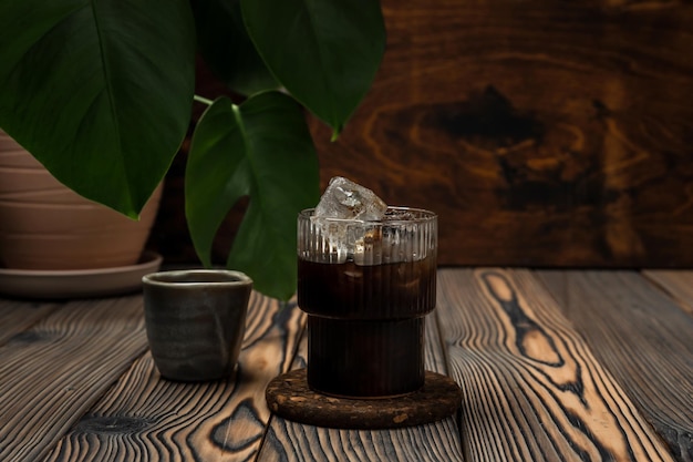 Latte gelado bebida refrescante de verão em preparação Um copo de café preto sobre fundo de madeira de jarro de gelo