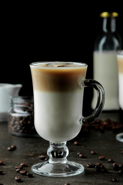 Latte de hielo o café helado con leche y cubitos de hielo en un vaso de precipitados sobre un fondo oscuro. bebida refrescante. bebida de verano.