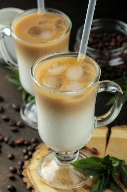 Latte de hielo o café helado con leche y cubitos de hielo en un vaso de precipitados sobre un fondo oscuro. bebida refrescante. bebida de verano.