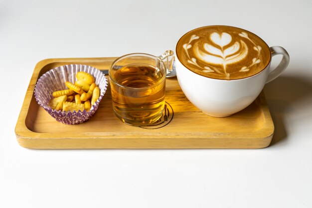 Latte-Kaffee oder Cappuccino-Kaffee in weißer Tasse mit schöner Baumherz-Latte-Kunst auf Holztisch.