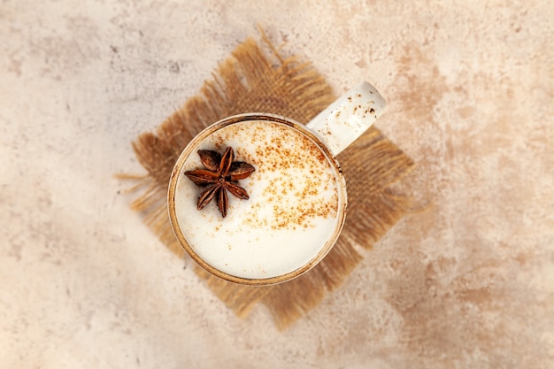 Latte Kaffeetasse mit Zimt und Sternanis auf beigem Weinlesepastellhintergrund, Draufsicht, Kopienraum