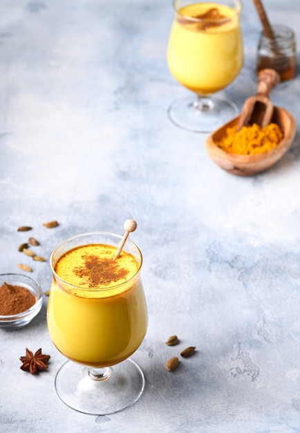 Latte de leche dorada de cúrcuma con ramas de canela y miel. Bebida ayurvédica saludable. Bebida detox natural asiática de moda con especias para veganos. Copie el espacio.