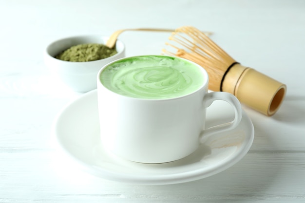 Latte matcha e acessórios para fazer na mesa de madeira branca