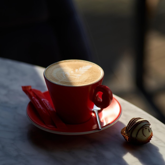 Latte o capuchino con espuma espumosa, taza de café en la mesa de la cafetería por la mañana.