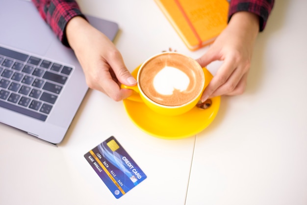 Latte quente arte em copo amarelo na mesa de trabalho