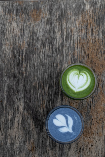 Latte de té verde y azul matcha en tazas. Bebida saludable. Bebida tradicional japonesa sobre fondo de madera negra. Lugar para el texto.