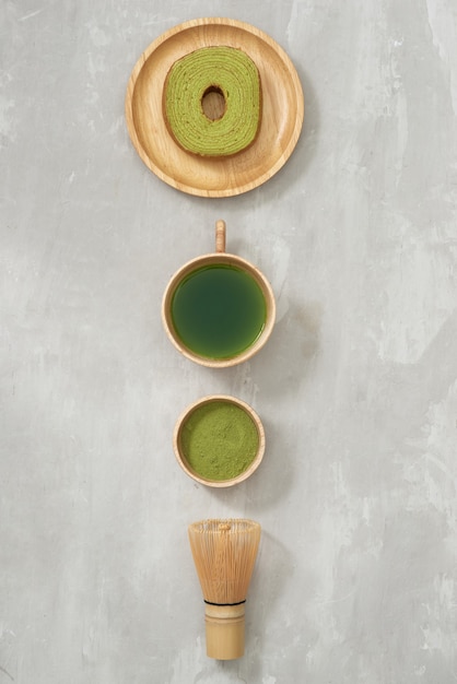 Latte de té verde matcha en una taza y utensilios para la ceremonia del té con pastel alemán. Copia espacio