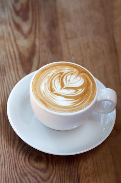 Lattekunstkaffee auf hölzernem Hintergrund