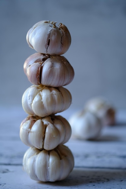 Lauch sativum. Haufen Knoblauch auf einem weißen Holztisch. Knoblauch ist ein Küchengewürz. Food-Fotokunst.