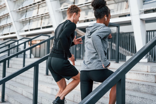 Laufen auf Tribünen Europäischer Mann und afroamerikanische Frau in sportlicher Kleidung trainieren zusammen