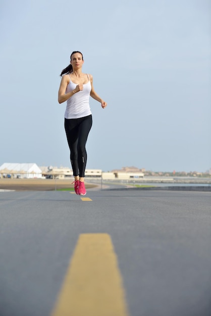 Laufen im Stadtpark. Frau Läufer draußen Joggen am Morgen mit Dubai urbane Szene im Hintergrund