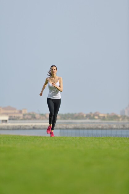 Laufen im Stadtpark. Frau Läufer draußen Joggen am Morgen mit Dubai urbane Szene im Hintergrund