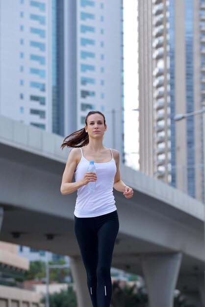 Laufen im Stadtpark. Frau Läufer draußen Joggen am Morgen mit Dubai urbane Szene im Hintergrund