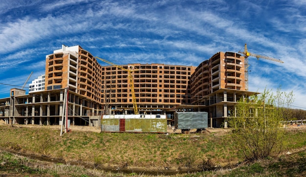 Laufende Arbeiten an einem neuen Wohnblock Hohes Gebäude im Bau mit Kränen Baustelle des neuen Gebäudes