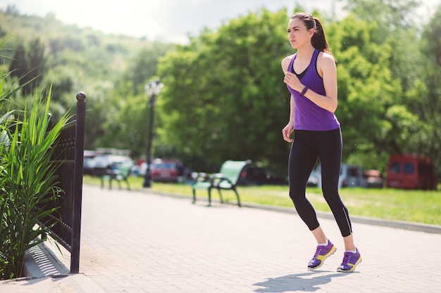 Laufende schöne Frau im Park Sonniger Tag Sport