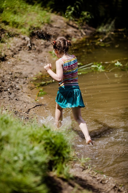 Laufendes kleines Mädchen im Sommer an einem sonnigen Tag im See