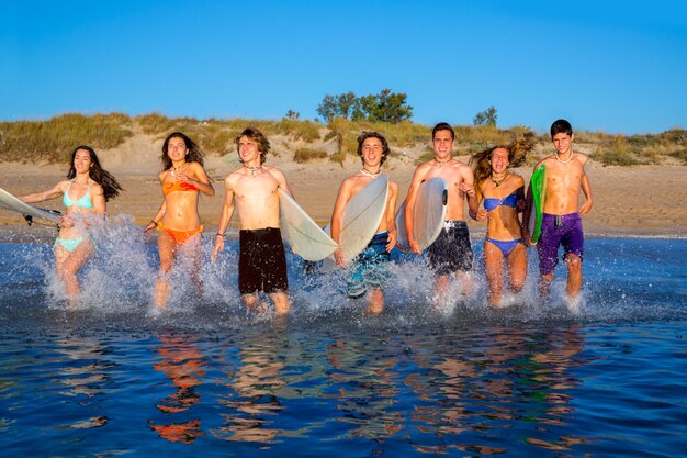 Laufendes Strandspritzen der Jugendlichersurfer-Gruppe