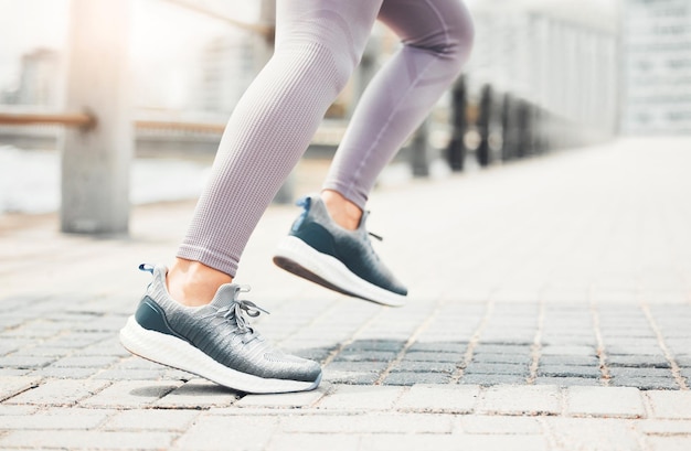 Laufschuhe Füße Turnschuhe und Cardio-Training in der Stadt Marathon und Sporttraining im städtischen Außenbereich Nahaufnahme der Sportlerin Fußbeine und schnelle Laufgeschwindigkeit der gesunden Fitness-Läufer-Sprintbewegung