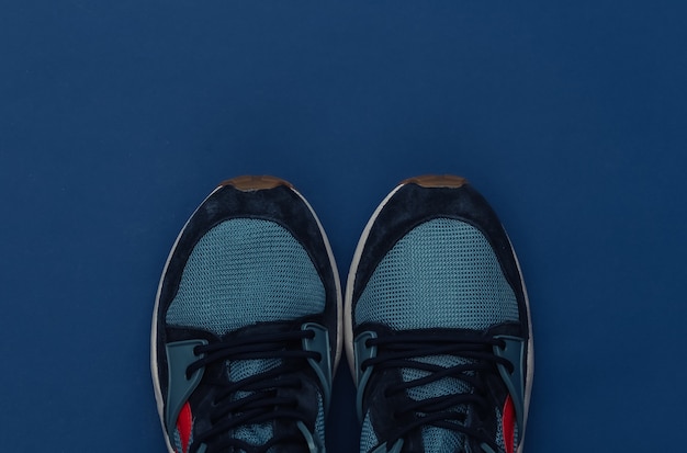 Laufschuhe (Turnschuhe) auf klassischem blauem Hintergrund. Gesunder Lebensstil, Fitnesstraining. Farbe 2020. Ansicht von oben