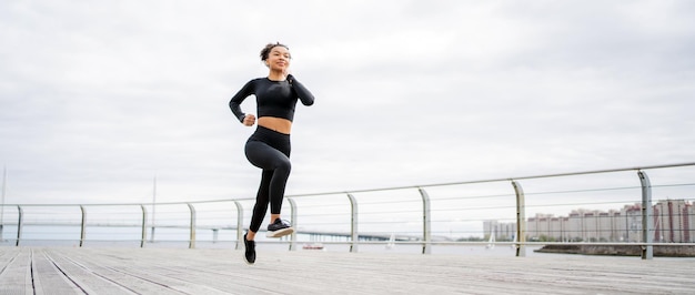 Laufsportlerin macht aktive Cardio-Fitnessübungen mit einer Fitnessuhr und einem Tracker