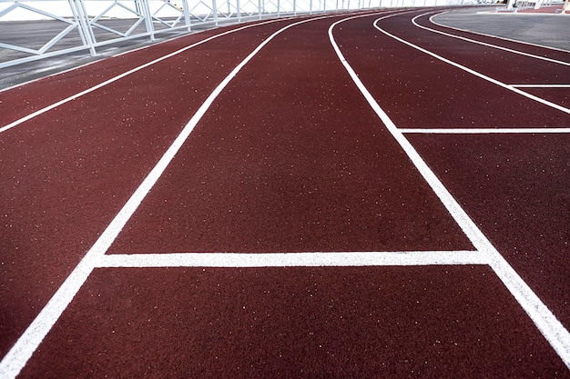 Laufstrecke Burgunder Laufstrecke mit weißen Streifen in einem Stadion ohne Menschen