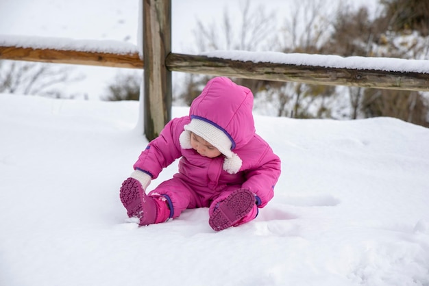 Laughing Baby Girl tumbado en la nieve profunda